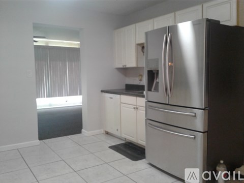 A kitchen with a black refrigerator and white cabinets.