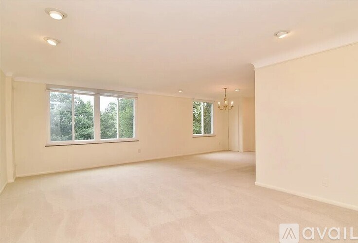 A spacious room with large windows and a chandelier.