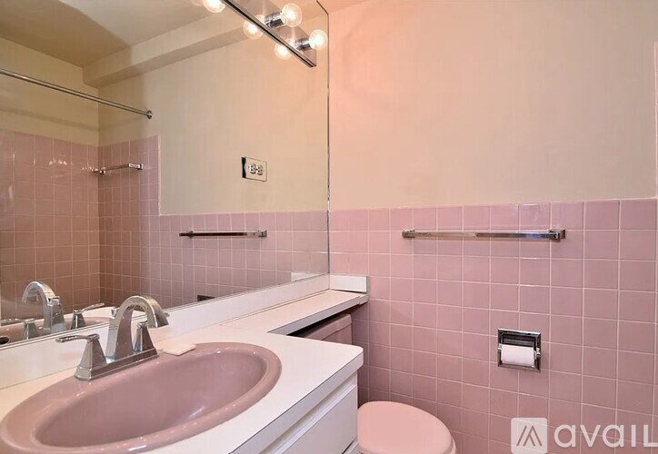 A bathroom with pink tiles and a white counter.