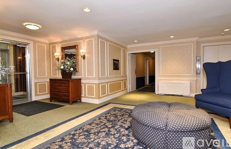 A living room with a blue sofa and a patterned ottoman.
