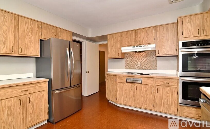 A kitchen with wooden cabinets and a stainless steel refrigerator.