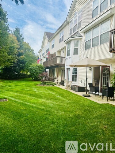A well-maintained lawn in front of a two-story house with a balcony.