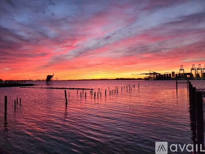 A beautiful sunset over a calm body of water with a dock in the distance.