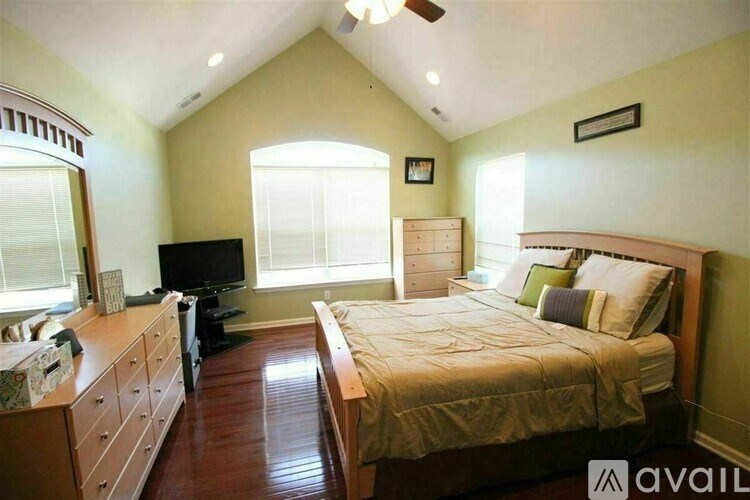 A bedroom with a bed, dresser, and television.