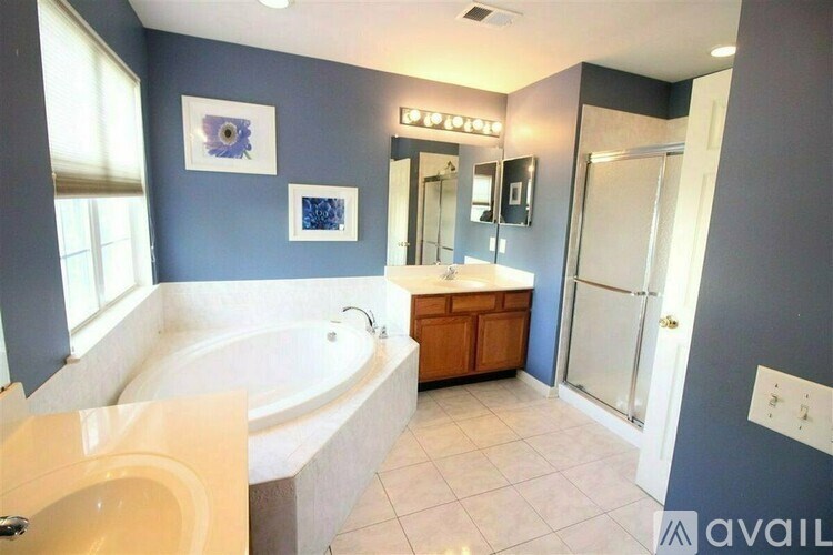 A bathroom with a tub, sink, and mirror.