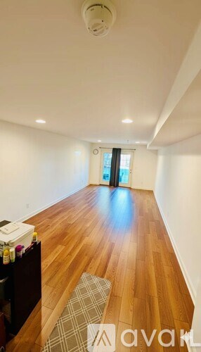 A long hallway with wood floors and a rug.