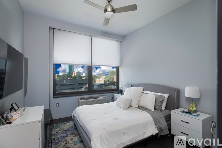 A bedroom with a large bed, a ceiling fan, and a window with blinds.