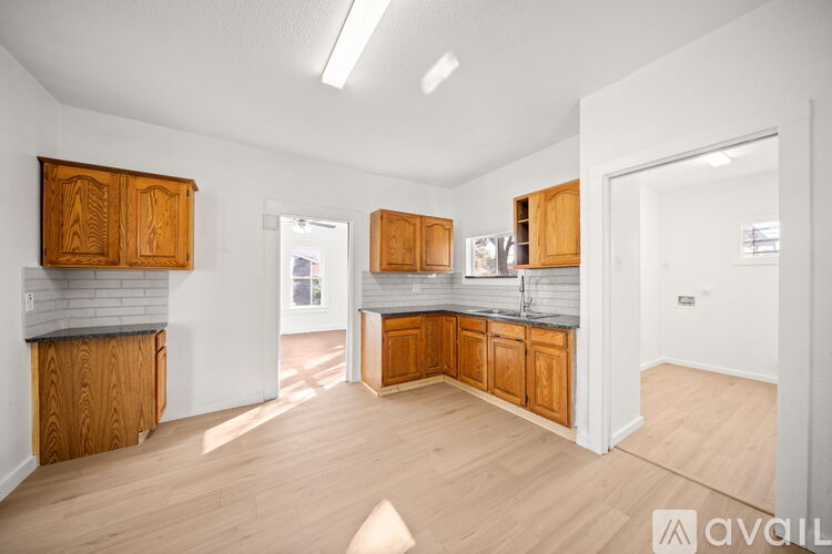 A kitchen with wooden cabinets and a grey backsplash is available for rent.