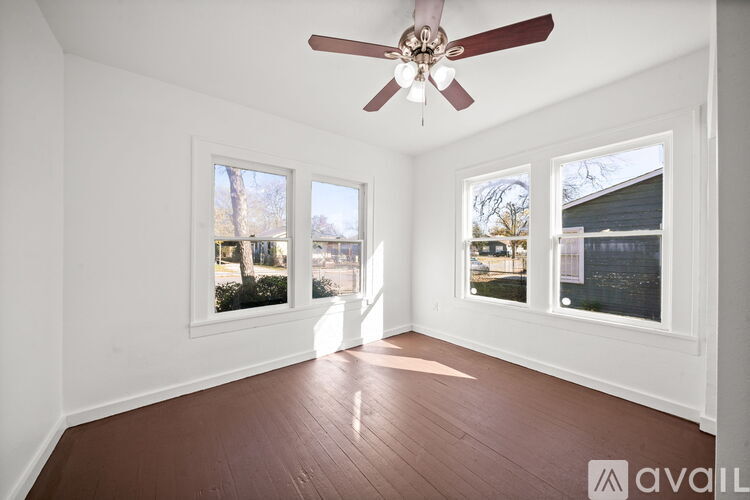 A room with a ceiling fan and three windows.
