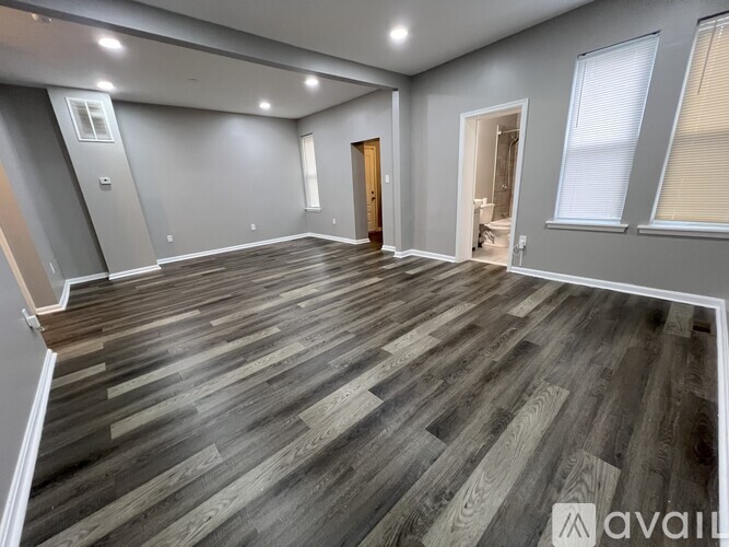 A spacious room with wooden flooring and a door on the right.