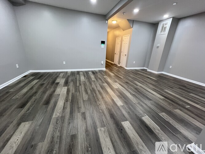 A room with wooden flooring and a doorway leading to another room.