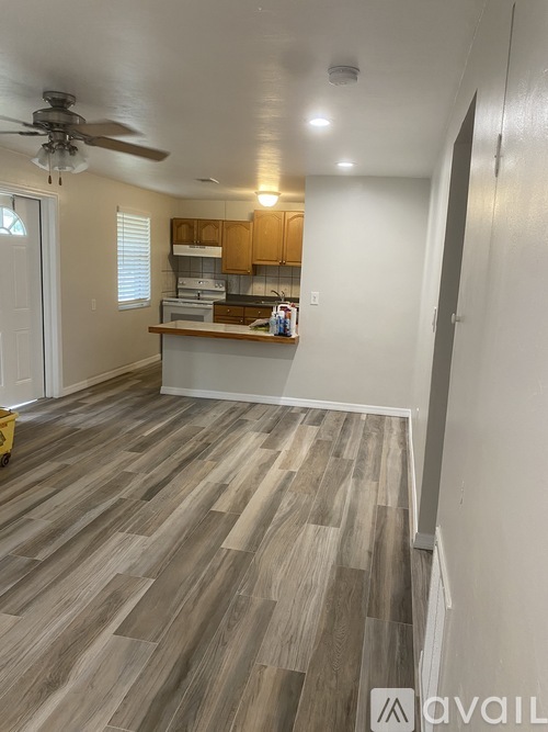 A kitchen with a fan on the ceiling and wooden flooring.