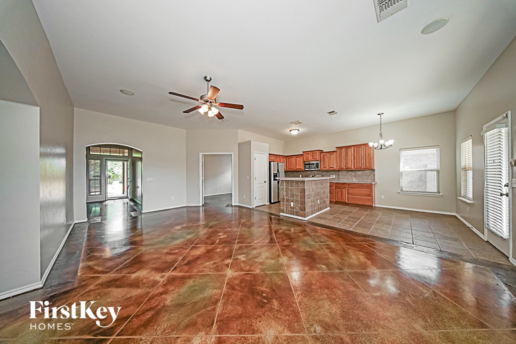 A spacious room with a fan and a brown floor.