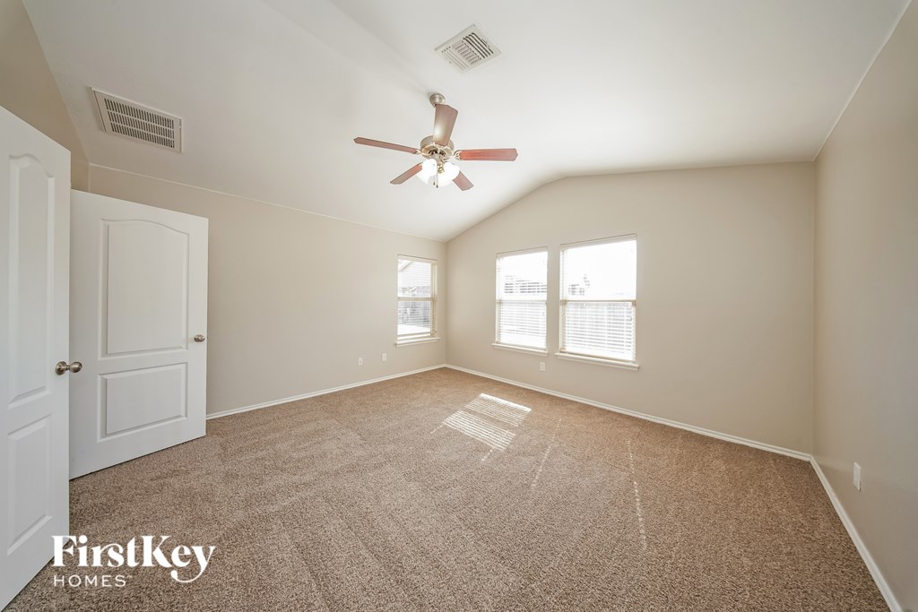 A room with a fan and carpeted floor.