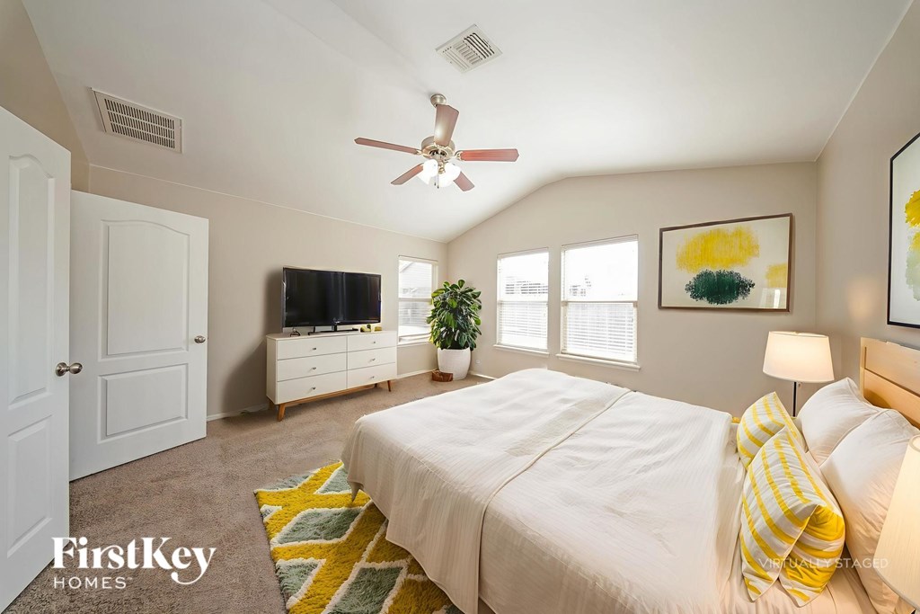 A bedroom with a bed, a ceiling fan, and a television.