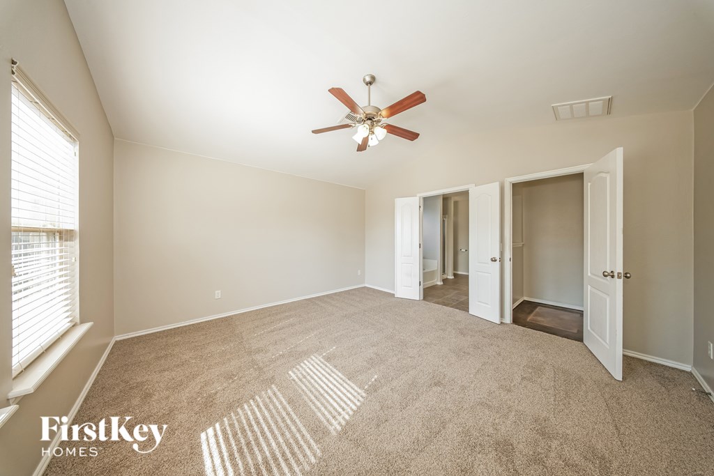 A spacious room with a fan and carpeted floor.