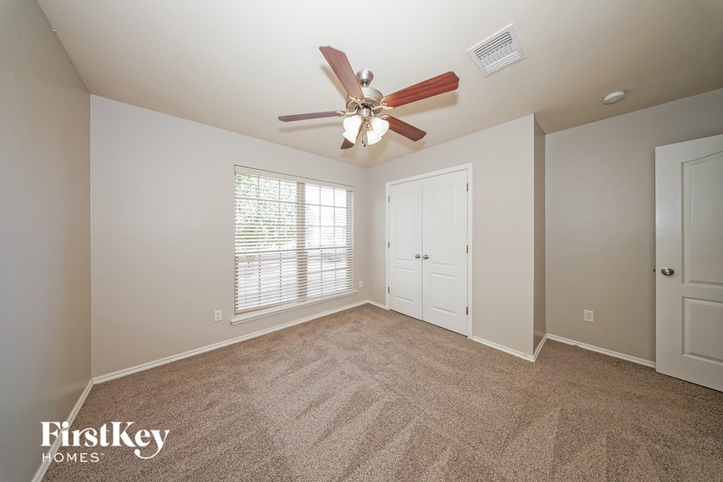 A room with a fan and carpeted floor.