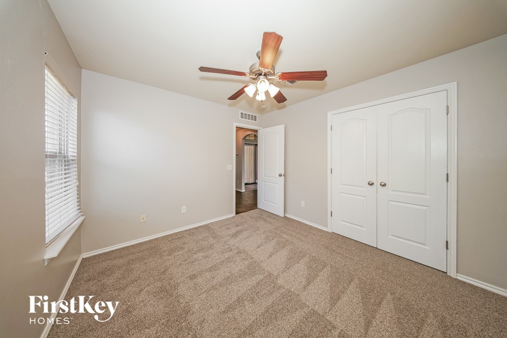 A room with a carpeted floor and a ceiling fan.