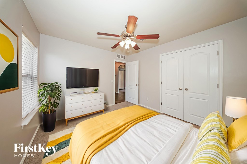 A bedroom with a bed, dresser, and a ceiling fan.