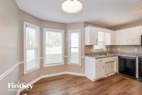 A kitchen with wooden floors and white cabinets.