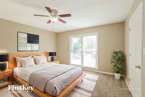 A bedroom with a bed, a ceiling fan, and a mirror on the wall.