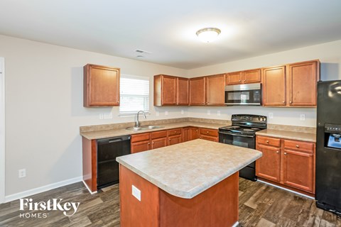 A kitchen with wooden cabinets and a black refrigerator.