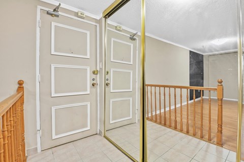 A white door with a gold handle is in a room with a wooden railing.