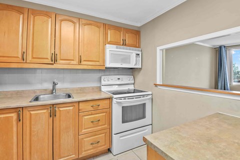 A kitchen with wooden cabinets and a white stove top oven.