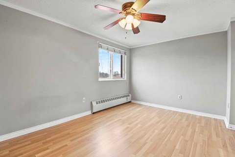 A room with a ceiling fan and a window with a view of the outdoors.
