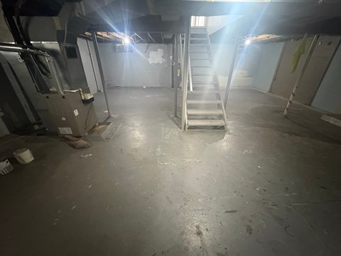 A dimly lit industrial space with a staircase and machinery.