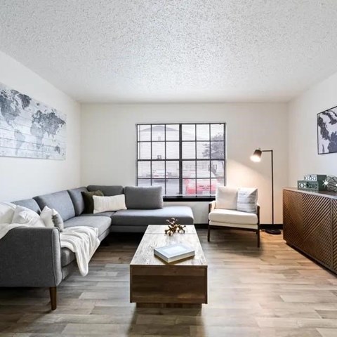 A living room with a grey couch, a white chair, and a wooden coffee table.