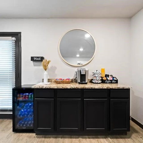 A black cabinet with a round mirror above it and a sign that says mail on the wall.