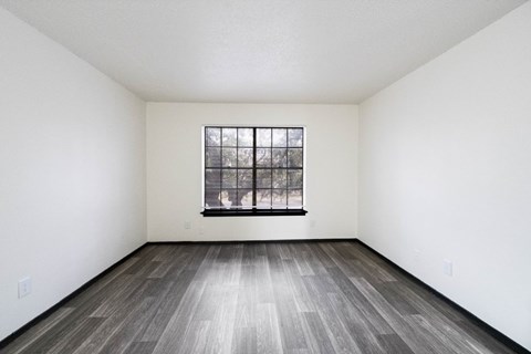 A room with a window and wooden flooring.