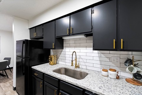 A kitchen with black cabinets and a white tiled backsplash.