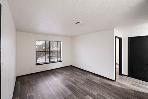 A room with a window and a wooden floor.