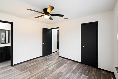 A room with a ceiling fan and two black doors.