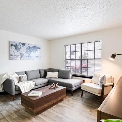 A living room with a grey couch, a wooden coffee table, and a world map on the wall.