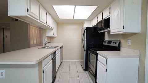 A kitchen with black appliances and white cabinets.