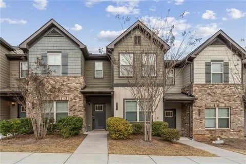 A row of houses with grey siding and stone accents.
