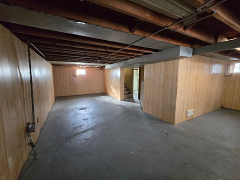 A sparsely furnished room with wooden walls and a concrete floor.