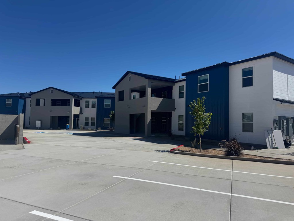 A parking lot in front of a building with blue and white exterior.