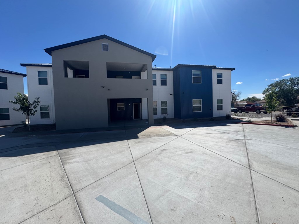 A sunny day at a parking lot with a building in the background.