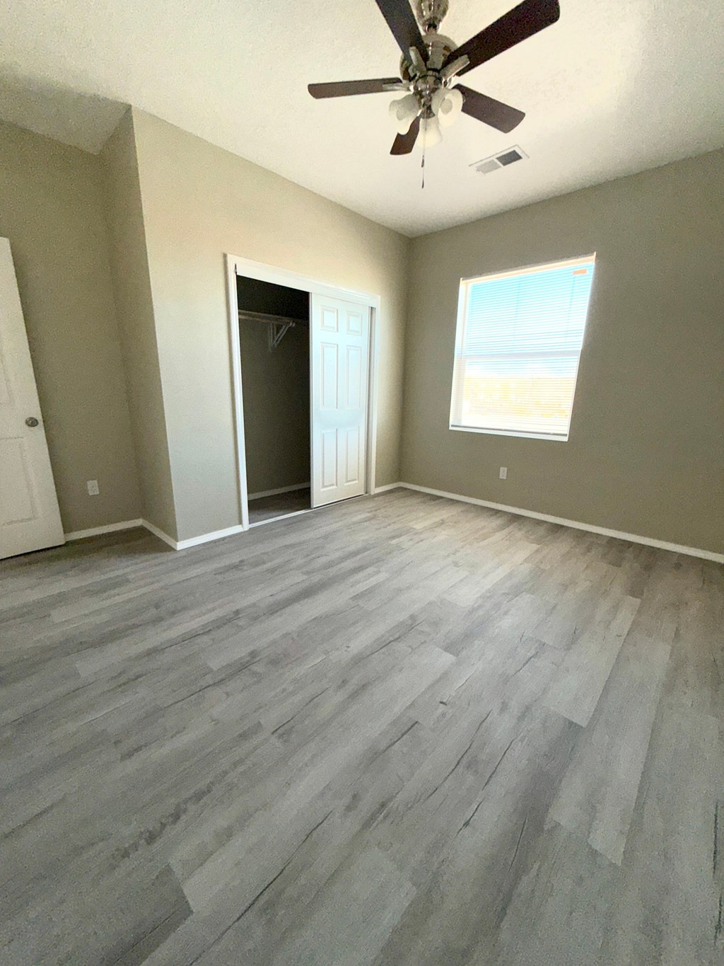 A room with a ceiling fan and a door leading to a balcony.