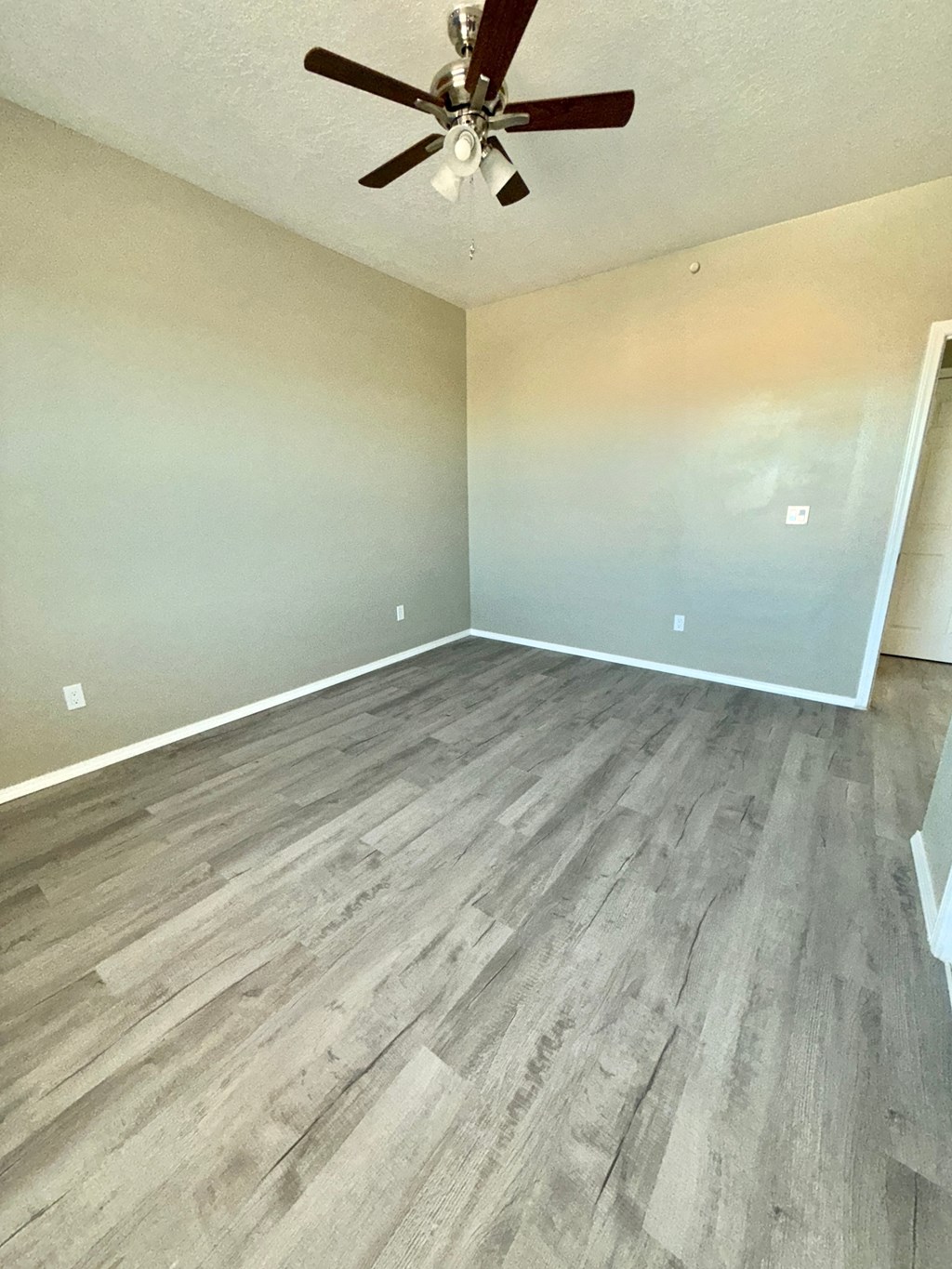 A room with a ceiling fan and wooden flooring.