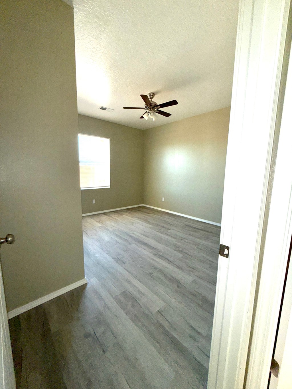 A room with a ceiling fan and light, and a door.