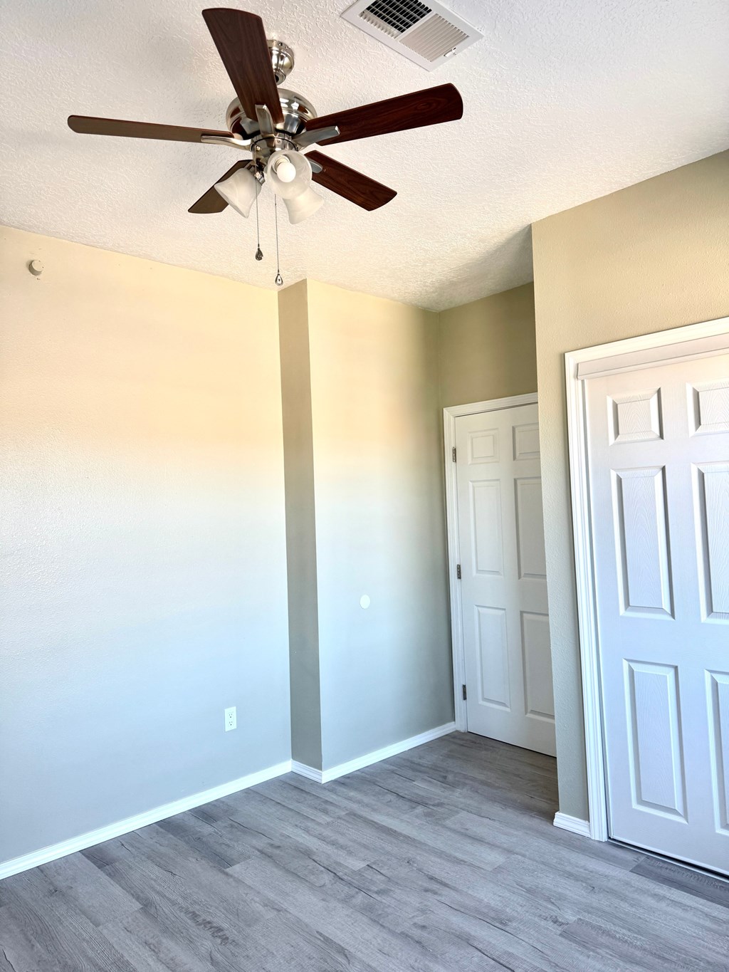 A room with a ceiling fan and a door.