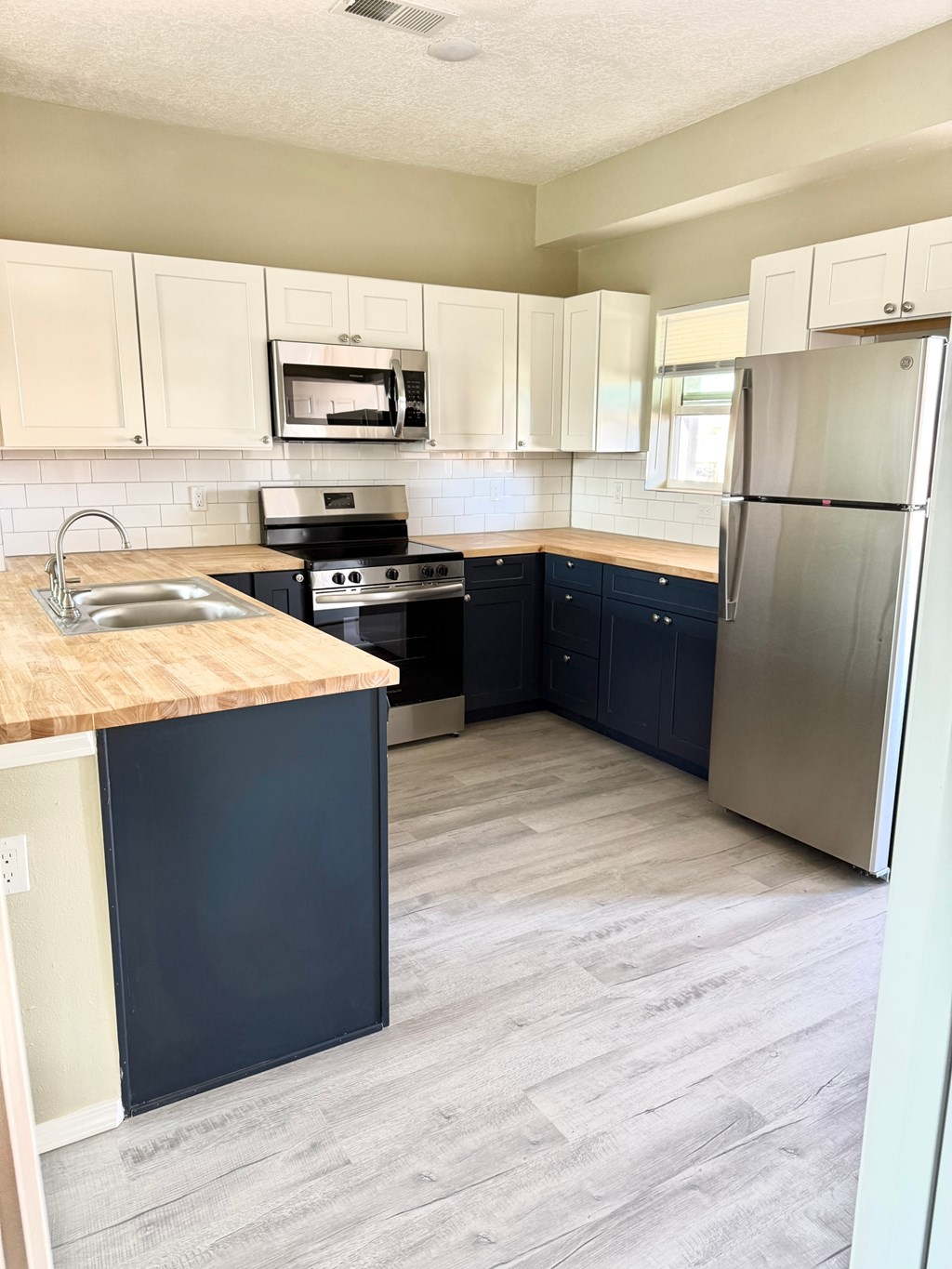 A kitchen with a stove, sink, and refrigerator.