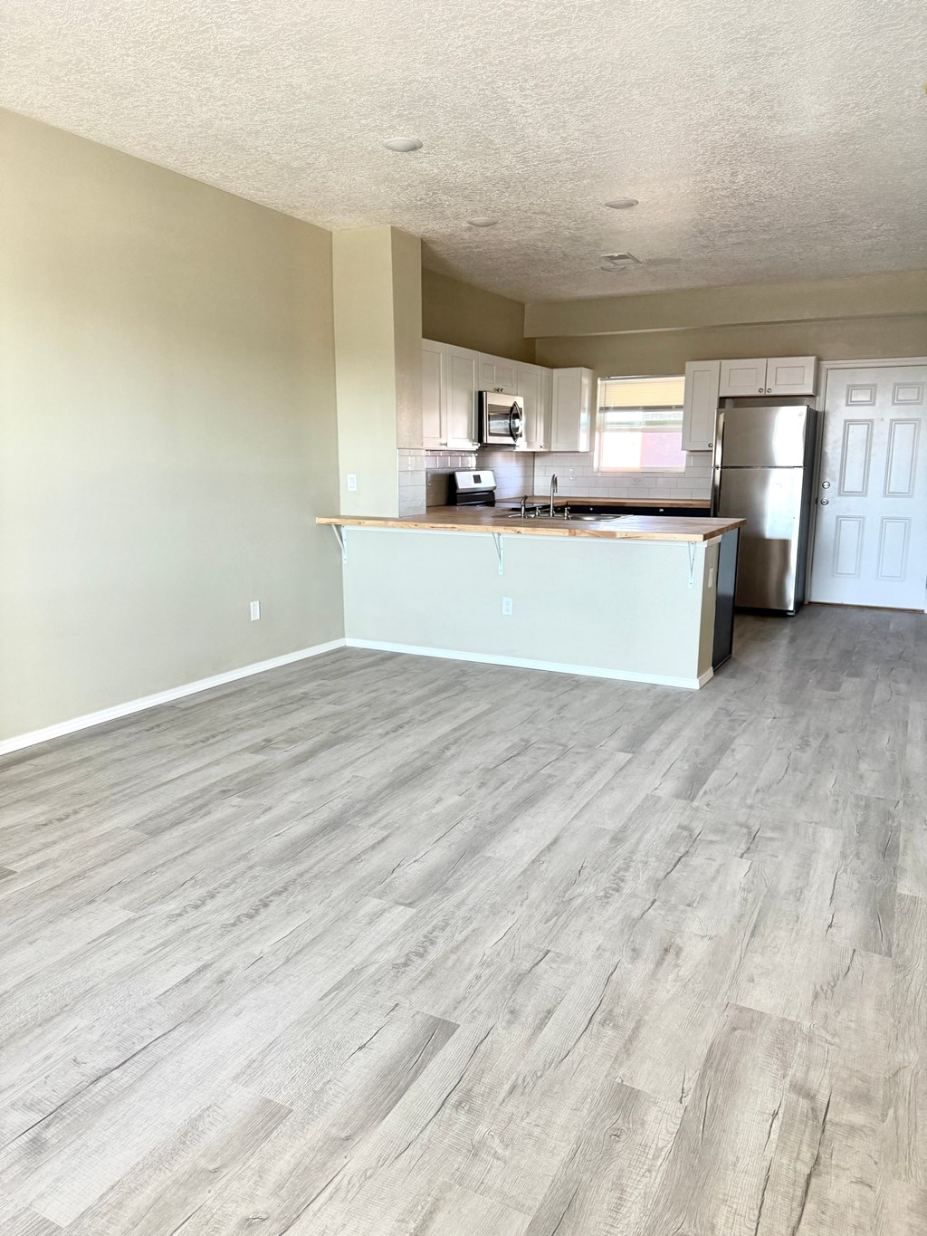 A kitchen with a white countertop and wooden flooring.