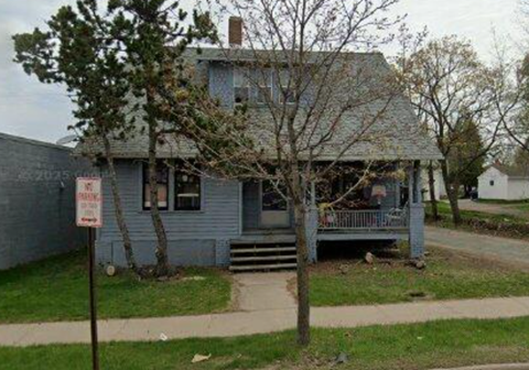 A blue house with a sign in front of it.
