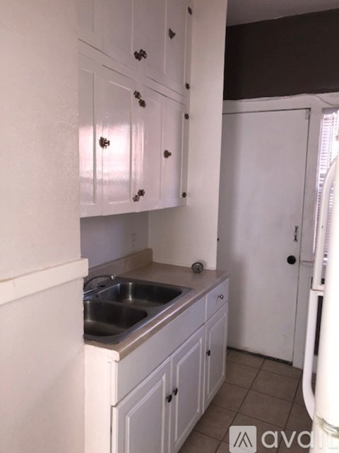 A kitchen with white cabinets and a white refrigerator.